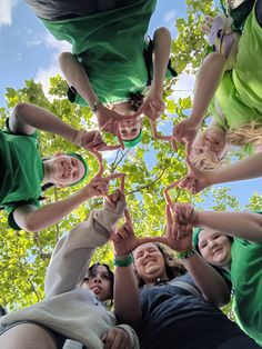 a group of people standing in the middle of a circle holding their hands together and smiling