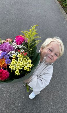 a young boy holding a bouquet of flowers