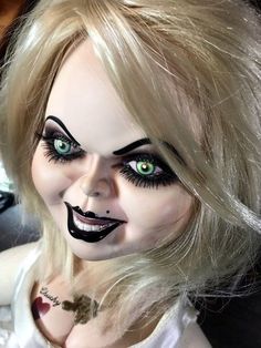 a creepy doll with green eyes and black makeup on it's face is posed for the camera