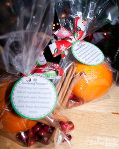 some oranges wrapped in plastic bags with christmas tags on them sitting on a table