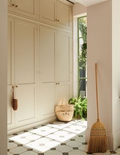 a broom sits on the floor in front of some cabinets and cupboards with windows