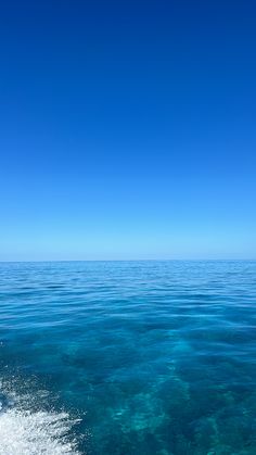 the water is crystal blue and clear with some waves coming in to shore as seen from a boat