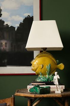 a fish lamp sitting on top of a wooden table next to a book and figurine