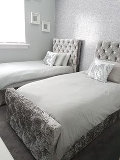 two beds in a room with silver and white decor on the headboard, foot board and foot board