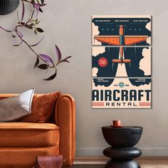 an airplane poster hangs on the wall above a couch in front of a chair and coffee table