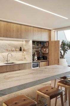 a kitchen with marble counter tops and stools next to an open window overlooking the ocean