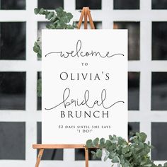 a welcome sign is on an easel with greenery in front of the door