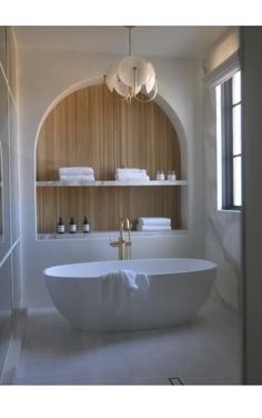 a large white bath tub sitting in a bathroom next to a shelf filled with towels