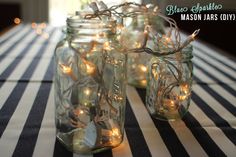 several mason jars filled with fairy lights on a striped tablecloth covered dining room table