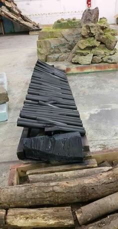 a pile of wood sitting on top of a cement floor next to a pile of logs