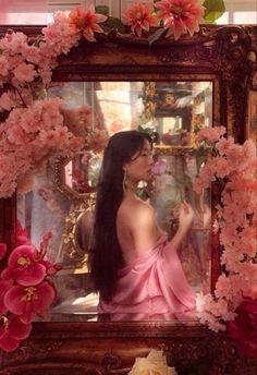 a woman sitting in front of a mirror surrounded by flowers