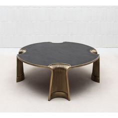 an unusual coffee table made out of wood and black marble top, with gold accents