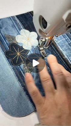 someone is using a sewing machine to sew flowers on denim jeans with the applique technique