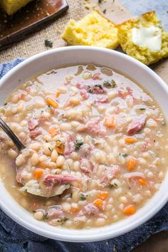 a white bowl filled with ham and bean soup on top of a blue napkin next to bread