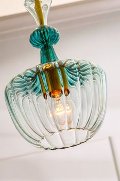 a glass light fixture hanging from the ceiling in a room with white walls and ceilings