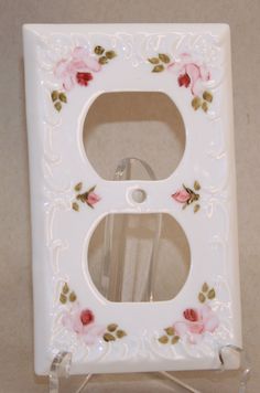 a white light switch plate with pink flowers on it and a glass holder for the cover