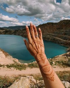 a woman's hand with hendix on it near a body of water