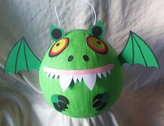 an ornament shaped like a green dragon with big eyes and sharp fangs on it's head