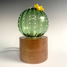 a green glass cactus sitting on top of a wooden stand