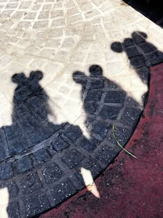 the shadow of two people standing next to each other on a brick walkway in front of a building