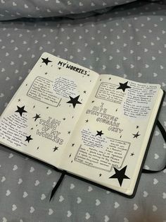 an open book with writing on it sitting on top of a bed covered in stars