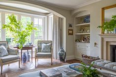 a living room filled with furniture and a fire place in front of a large window