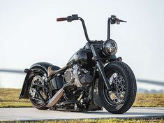 a black motorcycle parked on the side of a road next to grass and water in the background