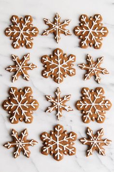 twelve snowflake cookies arranged on a marble surface