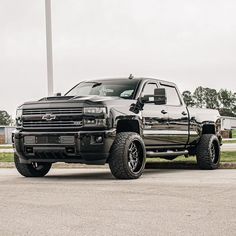 a large black truck parked on top of a parking lot next to a light pole