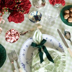 a table topped with plates and silverware next to red roses