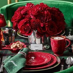 the table is set with red roses and silverware, cups, and saucers