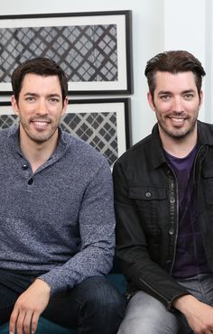 two men sitting next to each other in front of pictures on the wall behind them