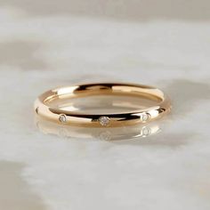 a gold wedding ring with three diamonds on it, sitting on a white marble surface