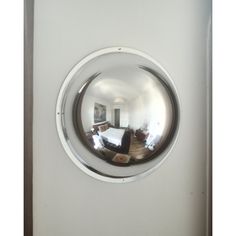 the reflection of a bed in a round mirror on a white refrigerator freezer door