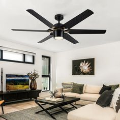 a living room with white furniture and black ceiling fans