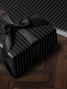 a large black gift box with a bow on it's side sitting on a wooden floor