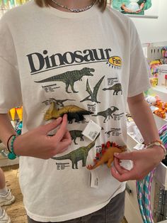 a person standing in front of a store display with dinosaurs on it's t - shirt