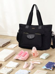 a black bag sitting on top of a wooden floor next to baby items and books