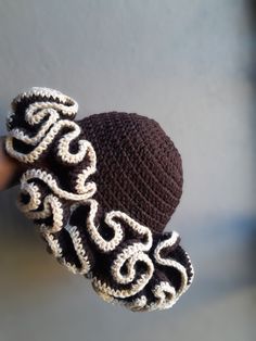 a crocheted hat is held up by someone's hand