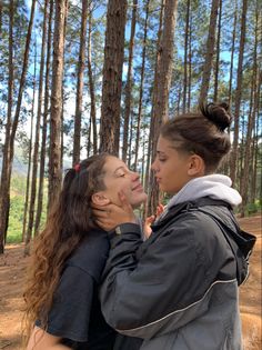 two women standing in the woods with their faces close to each other