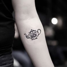 a black and white photo of a woman's arm with a teapot tattoo on it