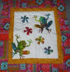 a quilted table cloth with colorful frogs on it