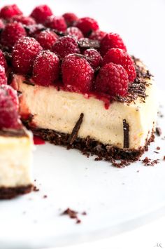 a cheesecake topped with raspberries on top of a white plate