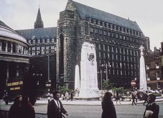 people are standing in front of a large building with a clock tower on the corner