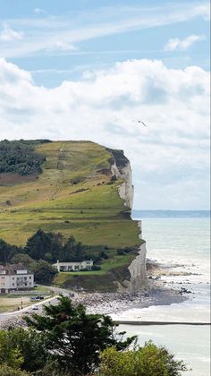 a view of the beach and cliffs from across the water with people walking on it