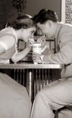 a man and woman sitting at a table drinking from cups