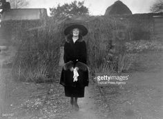 an old black and white photo of a woman wearing a hat with her hands in her pockets