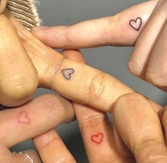 three fingers with hearts tattooed on them