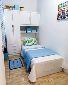 a small bedroom with a bed, cupboards and blue blanket on the floor in front of it