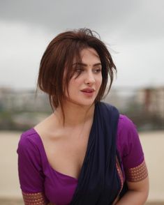 a woman in a purple top is posing for the camera